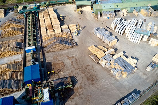 Aerial view of a sawmill yard with stacks of logs and lumber