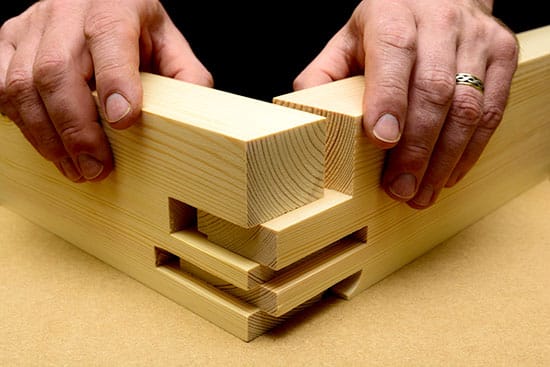 Hands fitting together an interlocking wooden corner joint