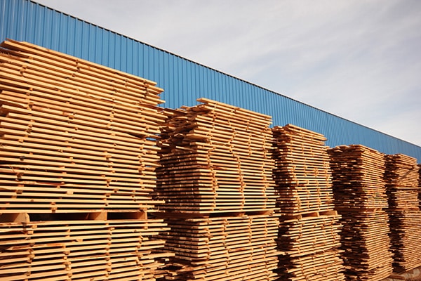 Stickered stacks of lumber drying outside a blue building