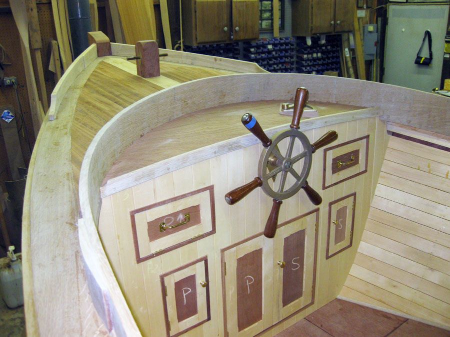 Wooden boat interior with a ship’s wheel and inlaid wood panels